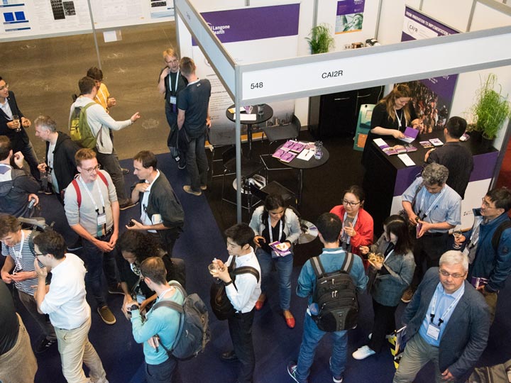 A crowd of attendees at around a booth at a scientific conference.